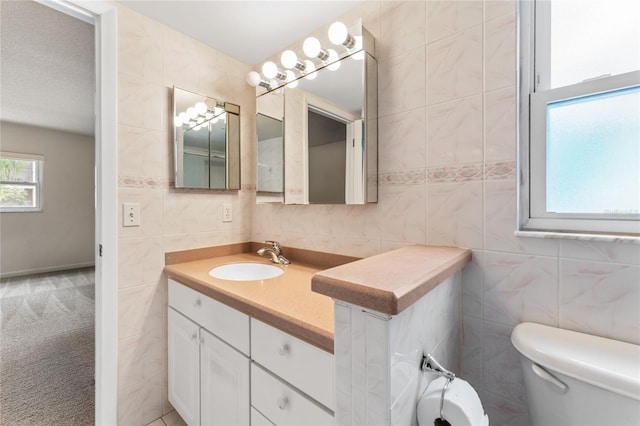 bathroom featuring tile walls, vanity, a textured ceiling, and toilet