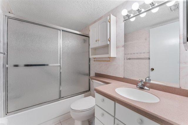 full bathroom with tile patterned flooring, combined bath / shower with glass door, a textured ceiling, toilet, and vanity