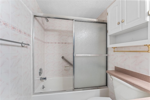 bathroom featuring tile walls, toilet, a textured ceiling, and combined bath / shower with glass door