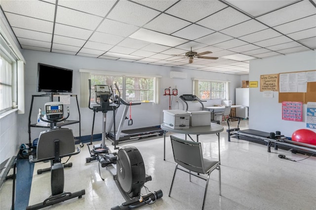 workout room featuring a paneled ceiling, ceiling fan, and a wall mounted AC