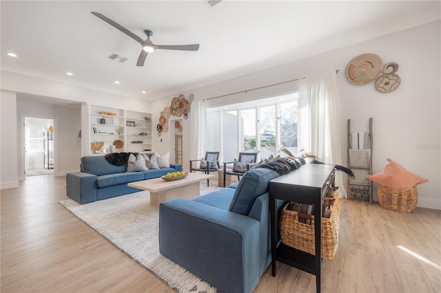 living room featuring built in shelves, ceiling fan, and light hardwood / wood-style floors