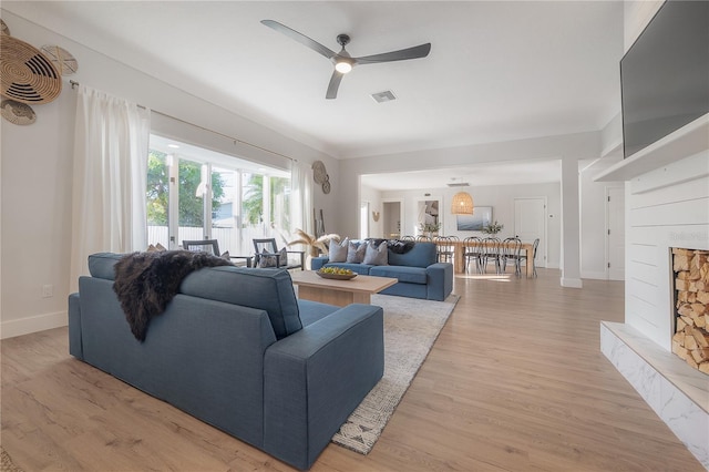 living room featuring ceiling fan, hardwood / wood-style flooring, and a premium fireplace