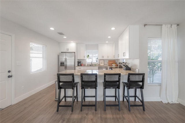 kitchen featuring white cabinets, plenty of natural light, a kitchen bar, and stainless steel appliances