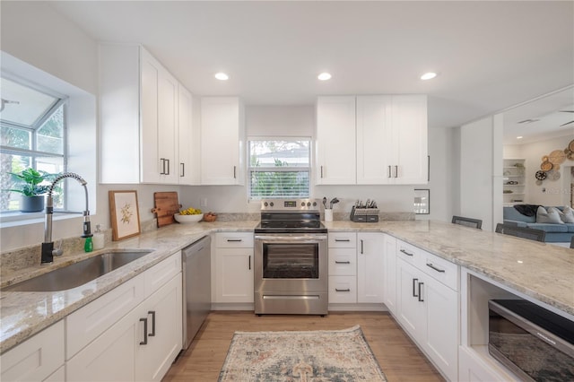 kitchen with light wood-type flooring, white cabinetry, stainless steel appliances, and sink