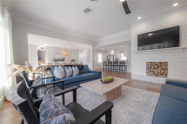 living room with a premium fireplace, hardwood / wood-style flooring, and ceiling fan