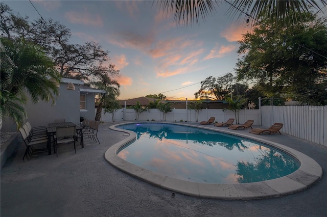 pool at dusk featuring a patio