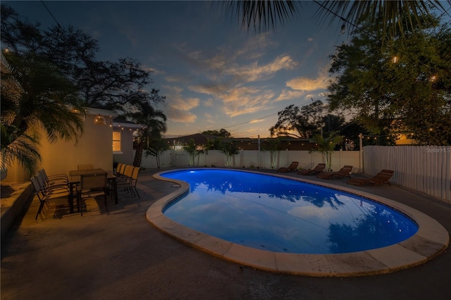 pool at dusk featuring a patio area