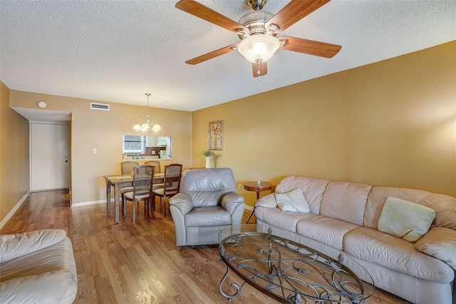 living room with a textured ceiling, ceiling fan with notable chandelier, and hardwood / wood-style flooring