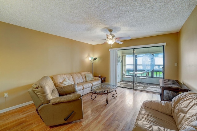 living room with ceiling fan, light hardwood / wood-style floors, and a textured ceiling