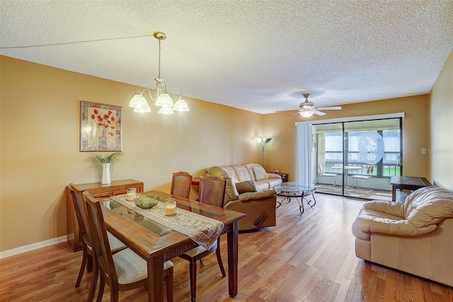 dining area featuring ceiling fan with notable chandelier, wood-type flooring, and a textured ceiling