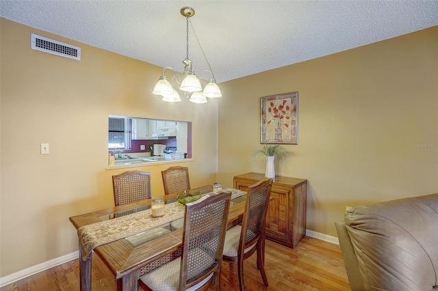 dining room featuring light hardwood / wood-style floors, a textured ceiling, and a chandelier