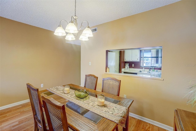 dining space with a notable chandelier, light hardwood / wood-style floors, and a textured ceiling