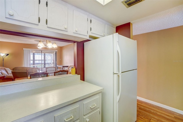 kitchen featuring white cabinets, white fridge, and light wood-type flooring