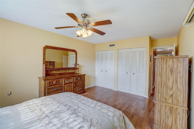 bedroom featuring multiple closets, ceiling fan, hardwood / wood-style floors, and a textured ceiling