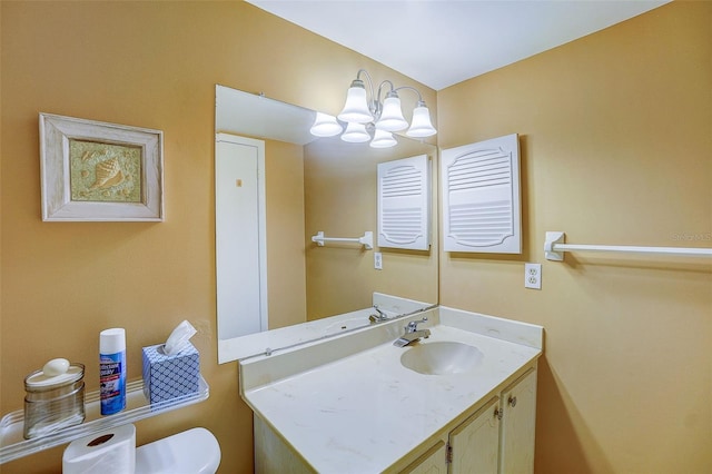 bathroom featuring vanity, a notable chandelier, and toilet