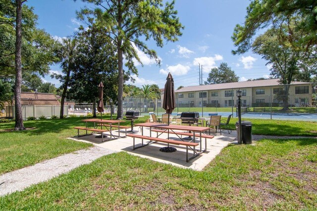 view of community featuring a lawn and tennis court