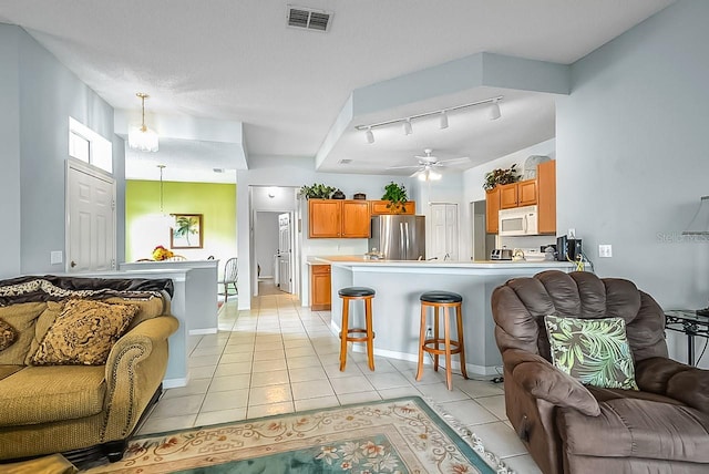 living room with ceiling fan, light tile patterned floors, a textured ceiling, and track lighting