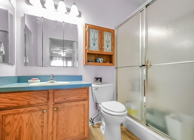 bathroom featuring ceiling fan, hardwood / wood-style floors, toilet, a shower with door, and vanity