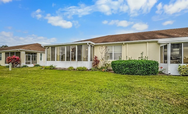 rear view of house with a lawn and a sunroom