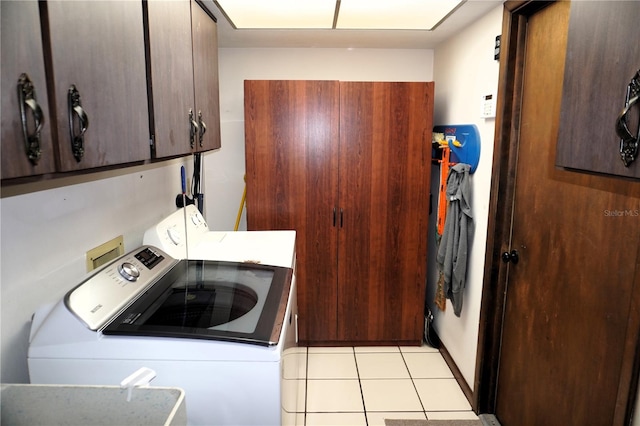 laundry area featuring washing machine and dryer, cabinets, sink, light tile floors, and washer hookup