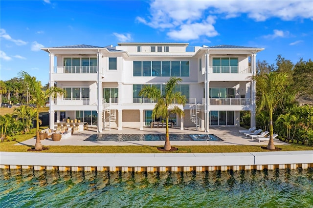 rear view of house with a patio, a water view, and a balcony