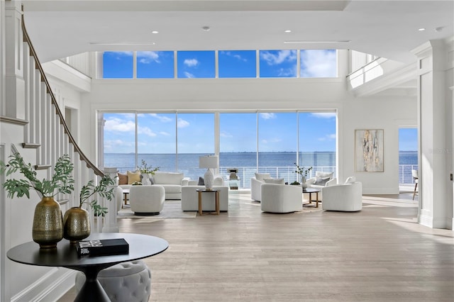 living room featuring a towering ceiling, plenty of natural light, and a water view