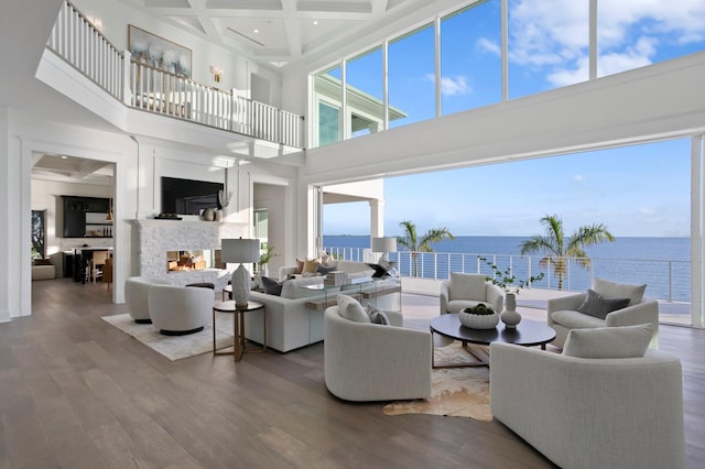 living room with wood-type flooring, coffered ceiling, a multi sided fireplace, beam ceiling, and a high ceiling