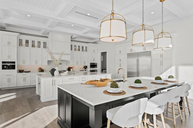 kitchen featuring beamed ceiling, appliances with stainless steel finishes, decorative light fixtures, and a spacious island