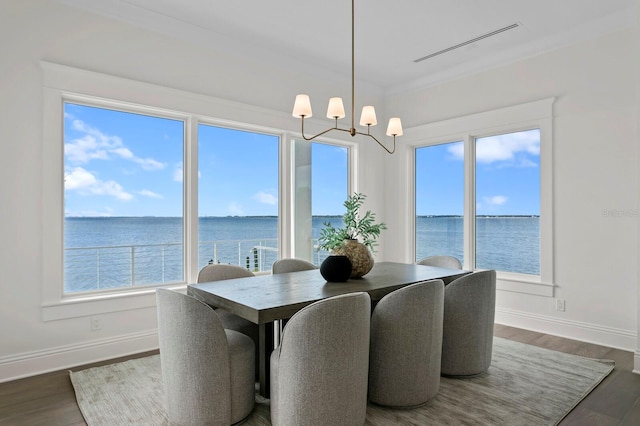 dining space with dark hardwood / wood-style flooring, a water view, and a notable chandelier