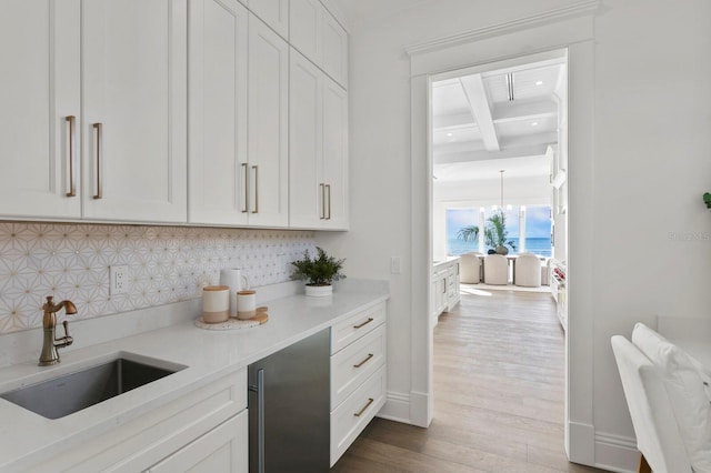 kitchen with wood-type flooring, beam ceiling, sink, and decorative backsplash