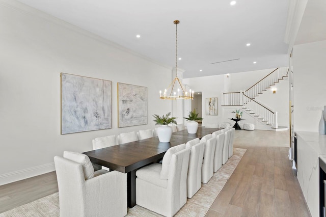 dining room with light wood-type flooring, a notable chandelier, and ornamental molding