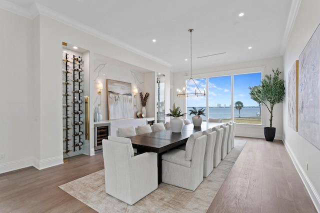 dining room featuring a chandelier, a water view, hardwood / wood-style flooring, and crown molding