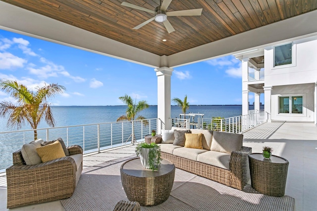 view of patio with ceiling fan, a balcony, a water view, and an outdoor living space