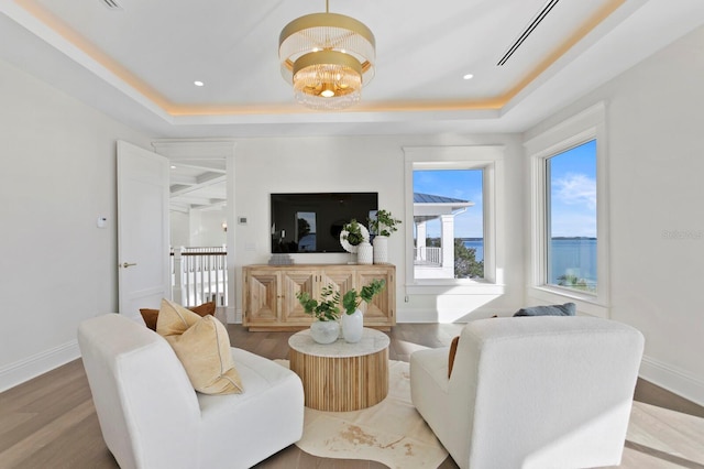 living room with a chandelier, a tray ceiling, and wood-type flooring