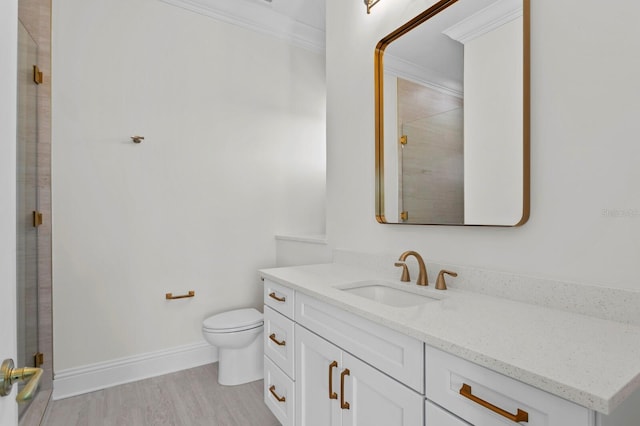 bathroom featuring toilet, hardwood / wood-style floors, ornamental molding, vanity, and walk in shower