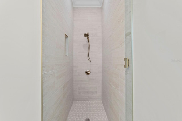 bathroom with tiled shower and crown molding