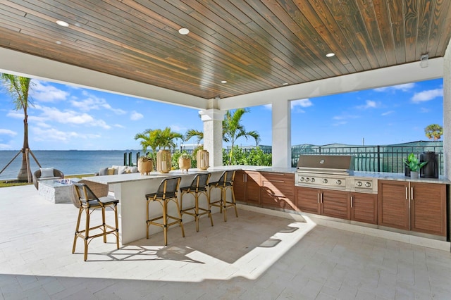 view of patio featuring exterior bar, a water view, a grill, and area for grilling