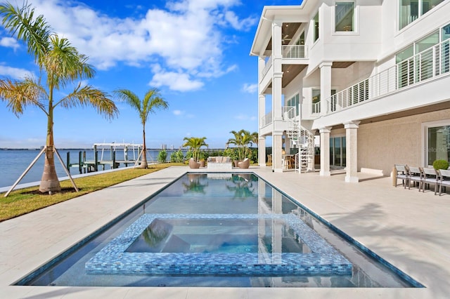 view of pool featuring an in ground hot tub, a water view, and a patio area