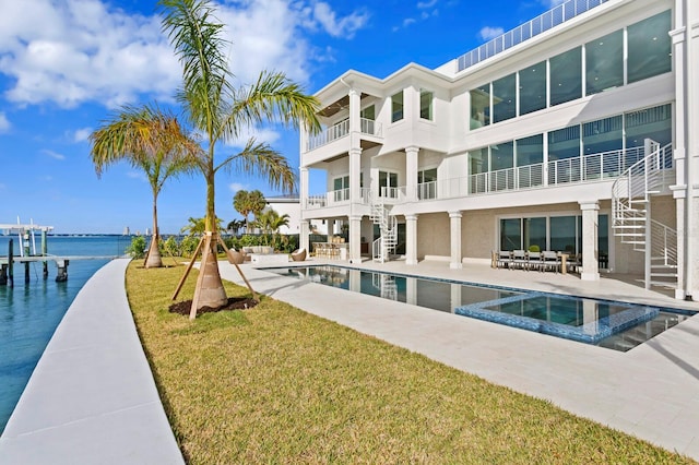 view of swimming pool featuring a water view, a lawn, and a patio