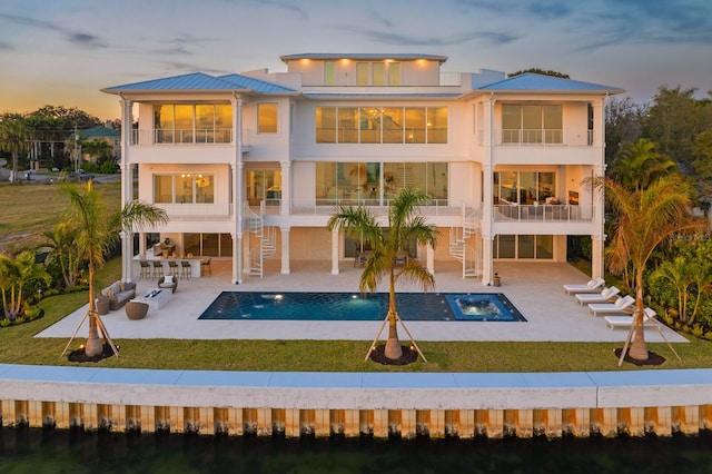 back house at dusk with a patio, a yard, and a balcony