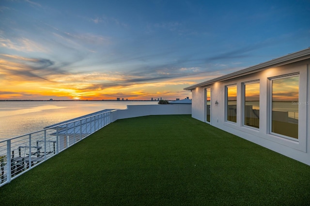 yard at dusk featuring a water view