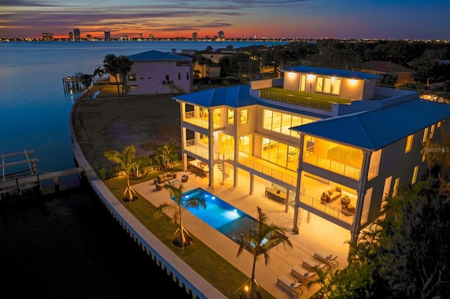 pool at dusk with a patio and a water view