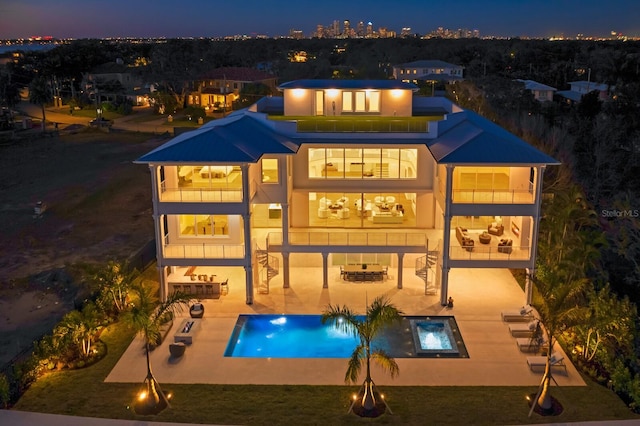 back of house with a patio, a swimming pool with hot tub, and a balcony