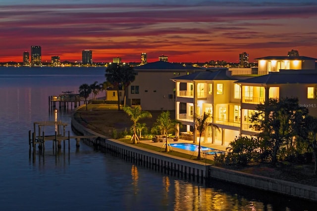 exterior space featuring a swimming pool with hot tub, a water view, a patio, and a balcony