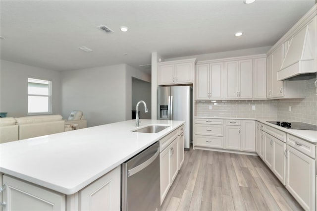 kitchen featuring backsplash, light wood-type flooring, custom exhaust hood, dishwasher, and black electric stovetop