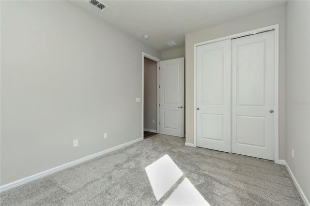 unfurnished bedroom featuring light carpet and a closet