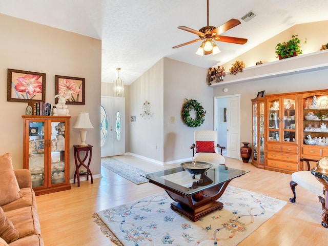 living room with light hardwood / wood-style floors, ceiling fan with notable chandelier, and vaulted ceiling