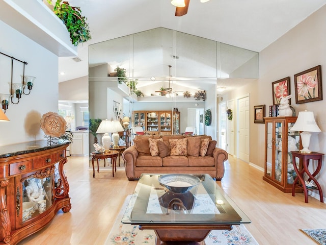 living room with ceiling fan, high vaulted ceiling, and light wood-type flooring