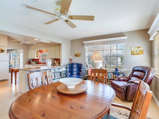 dining area featuring a textured ceiling, ceiling fan, and light hardwood / wood-style flooring