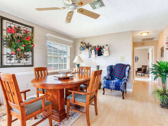 dining room featuring light hardwood / wood-style floors, a textured ceiling, and ceiling fan